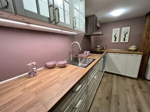 A modern kitchen with a wooden countertop, stainless steel sink, and white cabinets. - Idyllic Farm 1 (Wildensbuch)