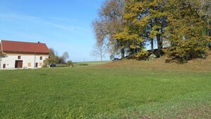 A rural house with a red roof, surrounded by a grassy field and trees with yellow leaves. - Authentic Jura farmhouse at the gateway to the Cascades du Hérisson (Saugeot)