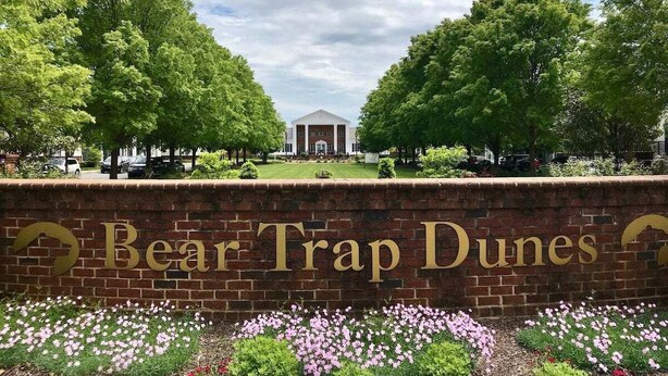A brick wall with 'Bear Trap Dunes' signage, surrounded by greenery and a clear sky. - Bear Trap Dunes * 4BR Luxury townhouse (Ocean View)