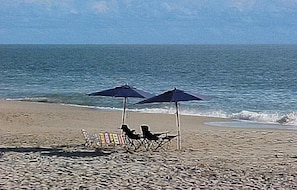 Une plage avec deux parasols et des chaises de plage.
