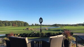 A patio with wicker furniture, a clock, and a view of a golf course. - Bear Trap Dunes * 4BR Luxury townhouse (Ocean View)