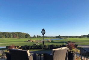 A patio with wicker furniture, a clock, and a view of a golf course. - Bear Trap Dunes * 4BR Luxury townhouse (Ocean View)