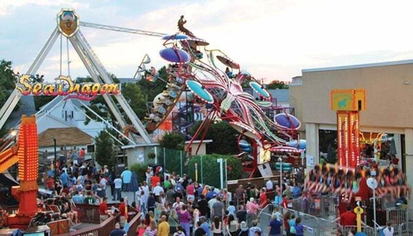 Un parque de atracciones concurrido, con diversas atracciones y una noria.