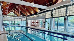 An indoor swimming pool with clear glass walls, a wooden ceiling, and a visible clock. - Bear Trap Dunes * 4BR Luxury townhouse (Ocean View)