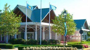 A building with a modern architectural design, featuring a prominent entrance with a covered area and multiple flags. - Bear Trap Dunes * 4BR Luxury townhouse (Ocean View)