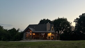 A rustic cabin with a stone chimney, a porch with outdoor seating, and a fireplace. - LODGE AT SADDLE RIDGE. Just five minutes from Hermann. (Hermann)