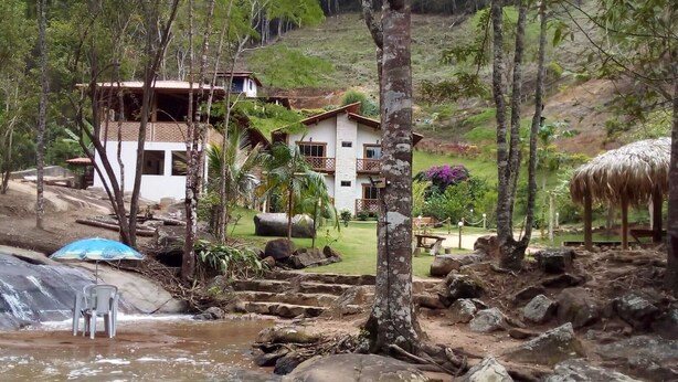 Ein Resort mit Pool, Wasserfall und einem mit Reeds gedeckten Gebäude.