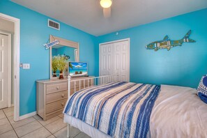A bedroom with a bed, a dresser, a mirror, a wall decoration, and a beach-themed picture.