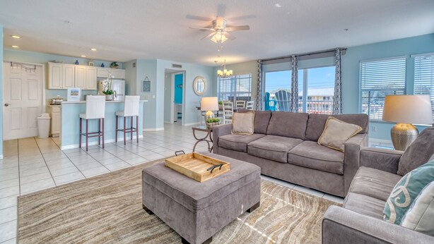 A spacious living room with a grey sofa, a wooden coffee table, and a dining area with white chairs. - Newly Remodeled Coastal Beachside Vacation Rental!! (Indian Rocks Beach)