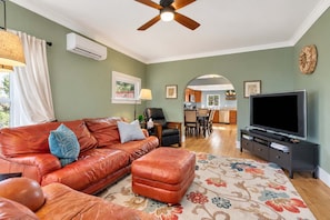 A living room with a leather sofa, ottoman, and a flat-screen TV. - Home Squared by LUX Retreats Paso (Paso Robles)