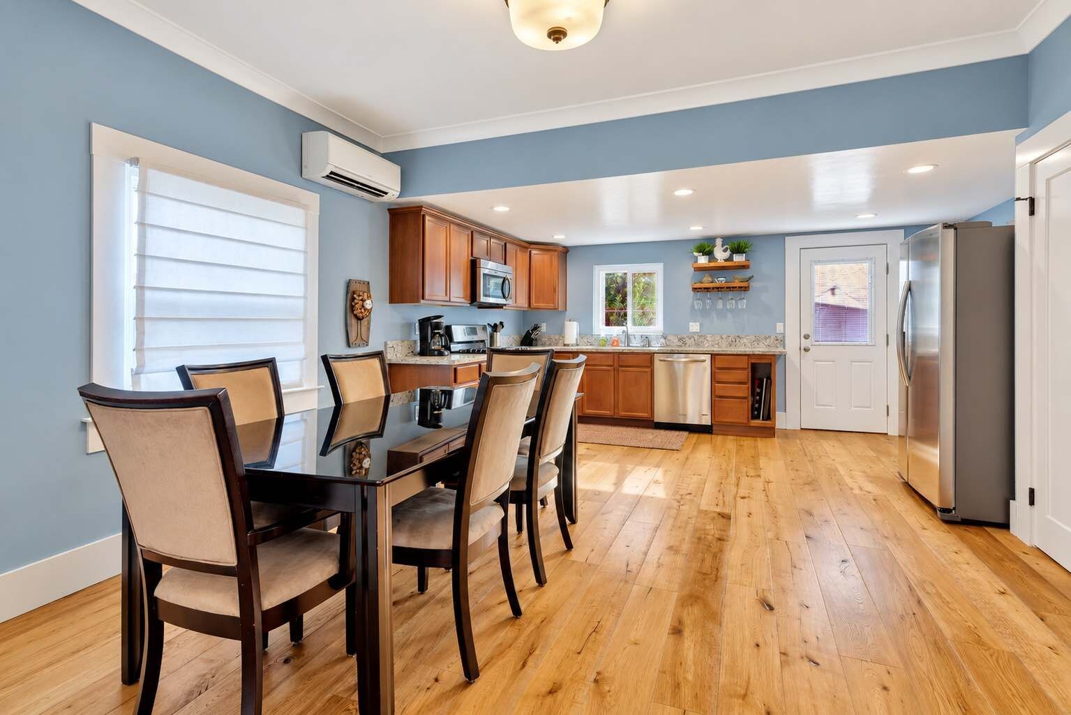 Una cocina moderna con armarios de madera, una mesa de comedor con sillas y un refrigerador.