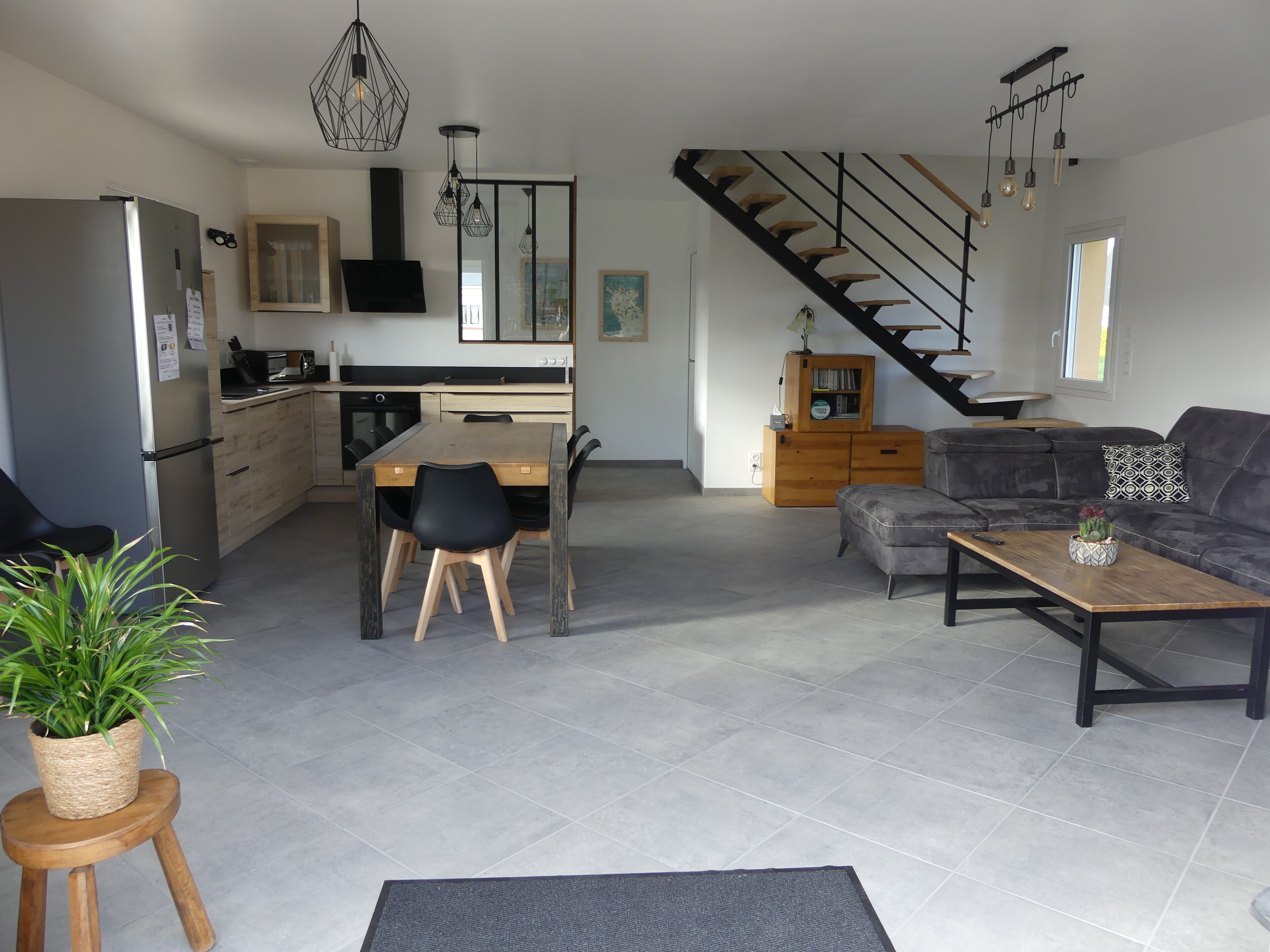 Una cocina moderna con comedor, un sofá gris y una escalera.