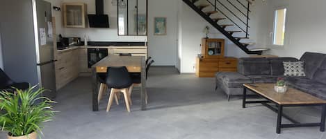 Una cocina moderna con comedor, un sofá gris y una escalera.