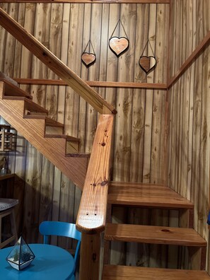 Un interior de madera con una escalera, una mesa y sillas.