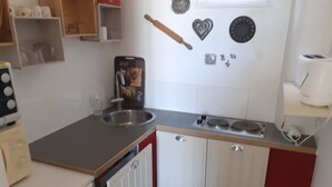 A compact kitchen with a sink, stove, and cabinets. - Cocon Tréportais (76470 Le Tréport)