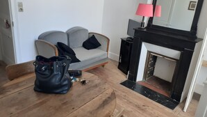 A living room with a sofa, a black leather bag, a wooden coffee table, a fireplace, and a mirror. - Cocon Tréportais (76470 Le Tréport)