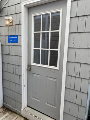 A gray door with a white frame and a window above it. A blue sign above the door reads "311 Water Street Apt. 3 & 4". - Riverview apt. in heart of downtown Saugatuck! (Saugatuck)