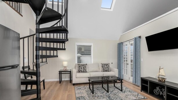 Una sala de estar moderna con una escalera, un sofá, una mesa de centro y un televisor montado en la pared.