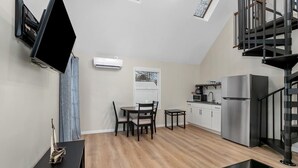 Una cocina moderna con estufa integrada, un refrigerador y un comedor con mesa y sillas.
