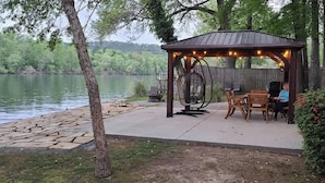 Ein Pavillon mit einer Schaukel, Sitzgelegenheiten im Freien und Blick auf einen See.