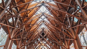 Eine Holzkonstruktion mit einem geometrischen Dach und mehreren Sitzreihen.