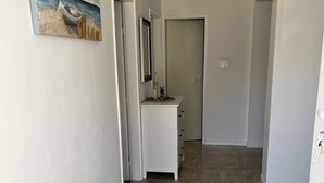 Um corredor com um aparador branco, um espelho e um quadro na parede.