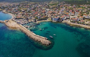 An aerial view of a coastal town with a marina, clear blue waters, and densely packed buildings. - Beachfront House Marlot (Razanac)