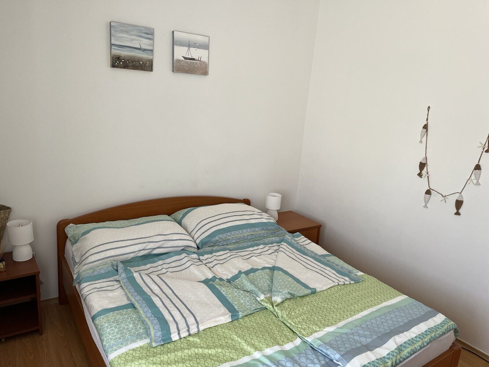 A bedroom with a bed, two bedside tables, a lamp, and wall art.