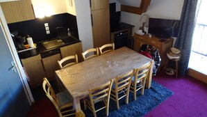 A compact kitchen with a dining area, wooden cabinets, and a small TV. - Duplex 6-8 people Saint François Longchamp (Saint-François-Longchamp)