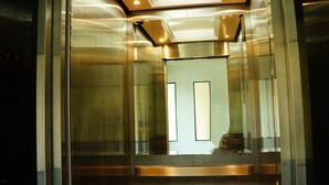 An elevator interior with metallic walls and a reflective floor. - P.T. Grand Hotel (Kanchanaburi)