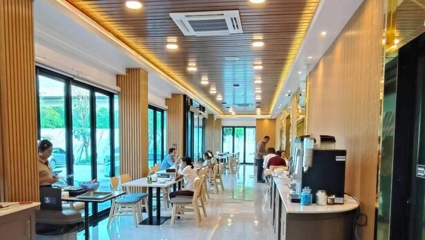 A spacious, modern restaurant with a long counter, ample seating, and a clean, polished floor. - P.T. Grand Hotel (Kanchanaburi)