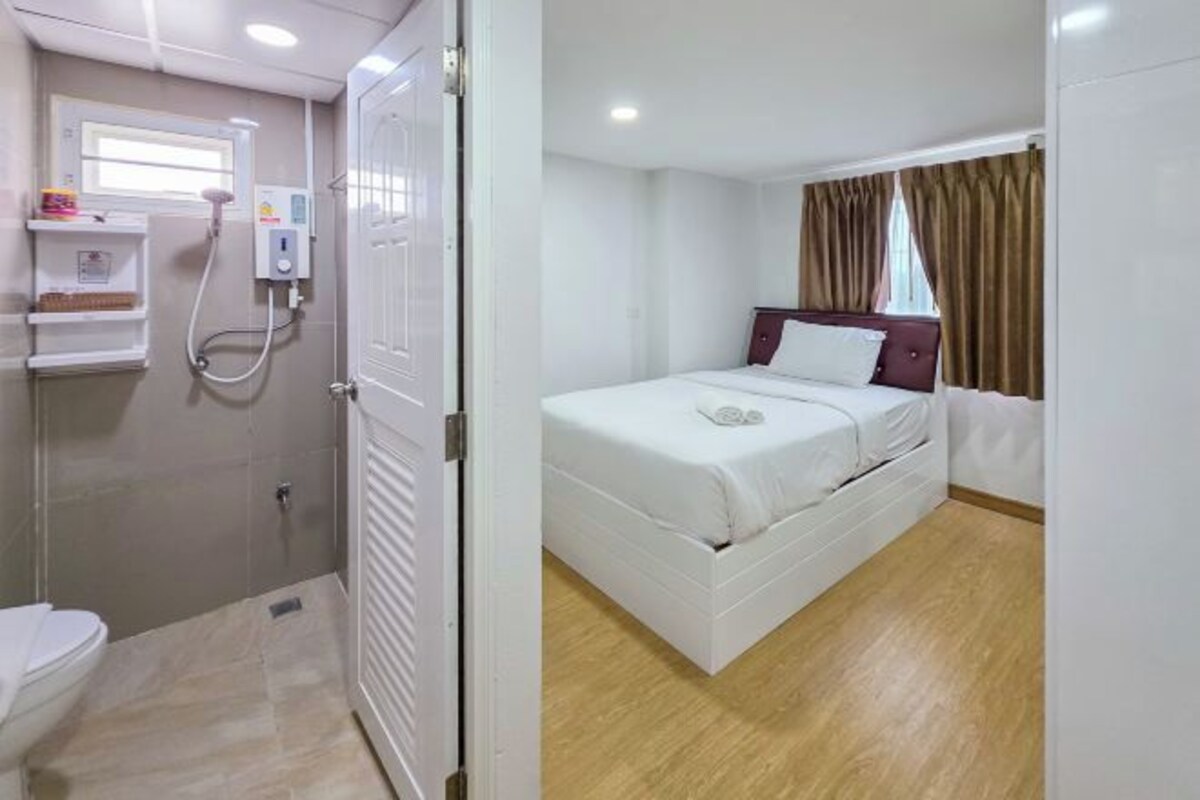 A hotel room with a bed, a shower, and a toilet.