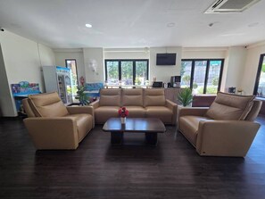 A spacious room with a sofa set, a coffee table, and a television. - P.T. Grand Hotel (Kanchanaburi)