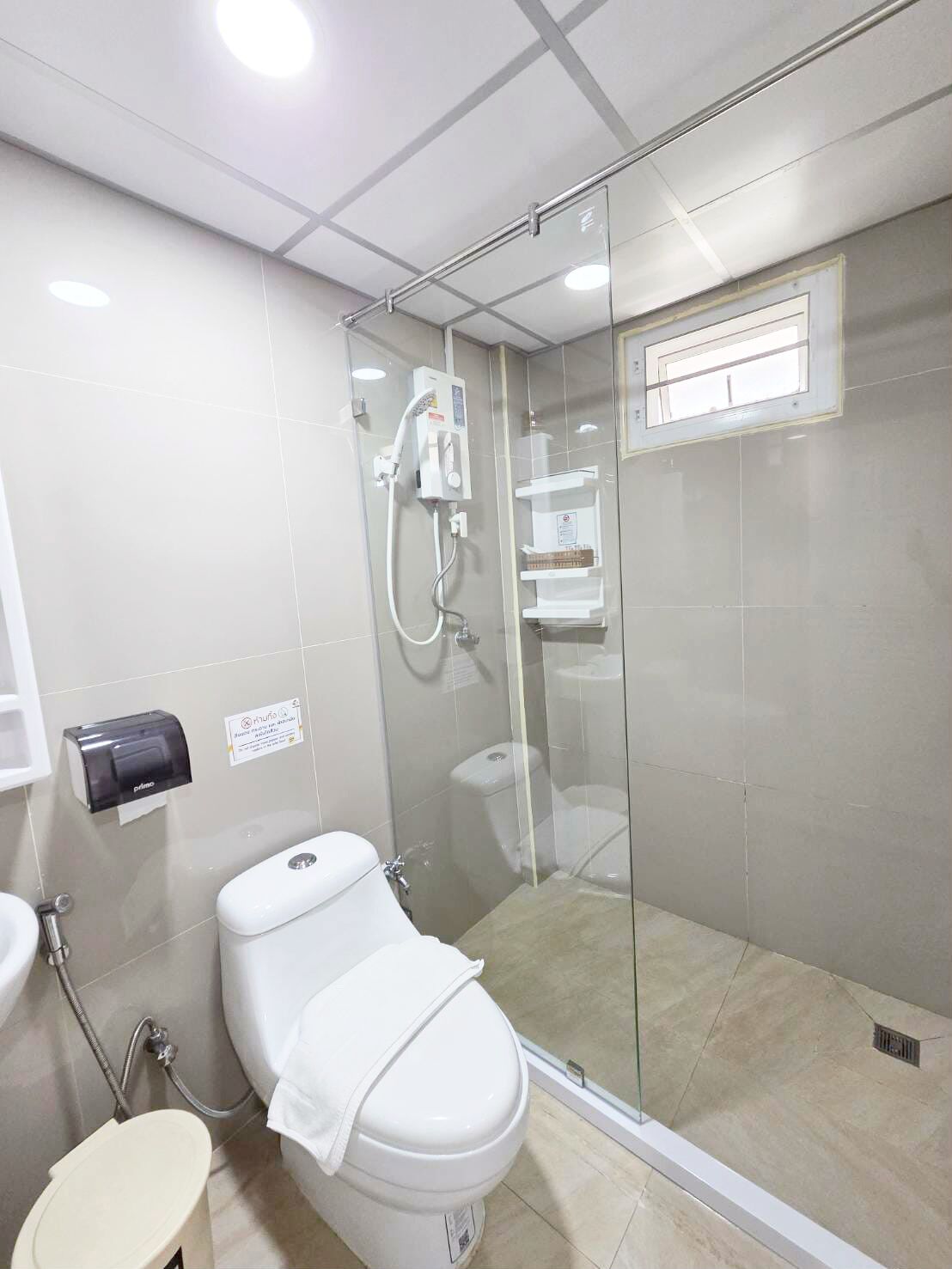 Une salle de bain moderne dotée d’une douche à parois de verre, de toilettes et d’un lavabo.