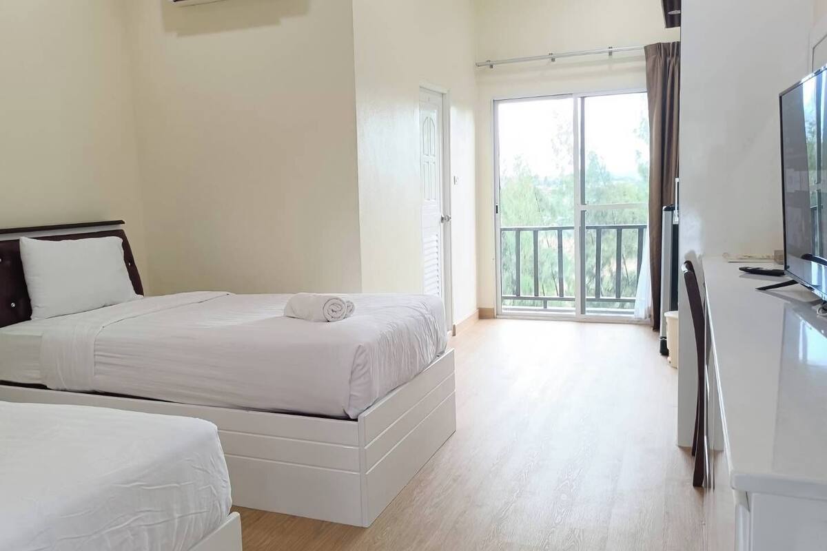 A hotel room with two beds, a TV, and a balcony with a view.