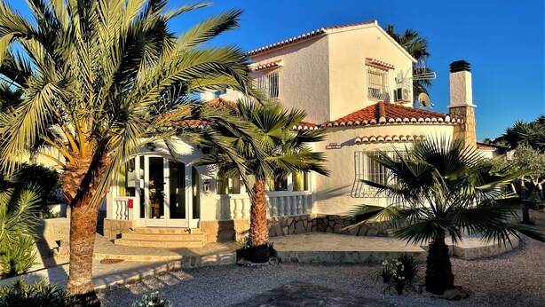 Une villa de style méditerranéen avec une façade en pierre, un toit en tuiles et une allée gravillonnée.