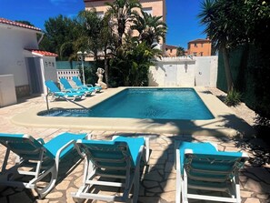 Una piscina con sdraio e una statua.