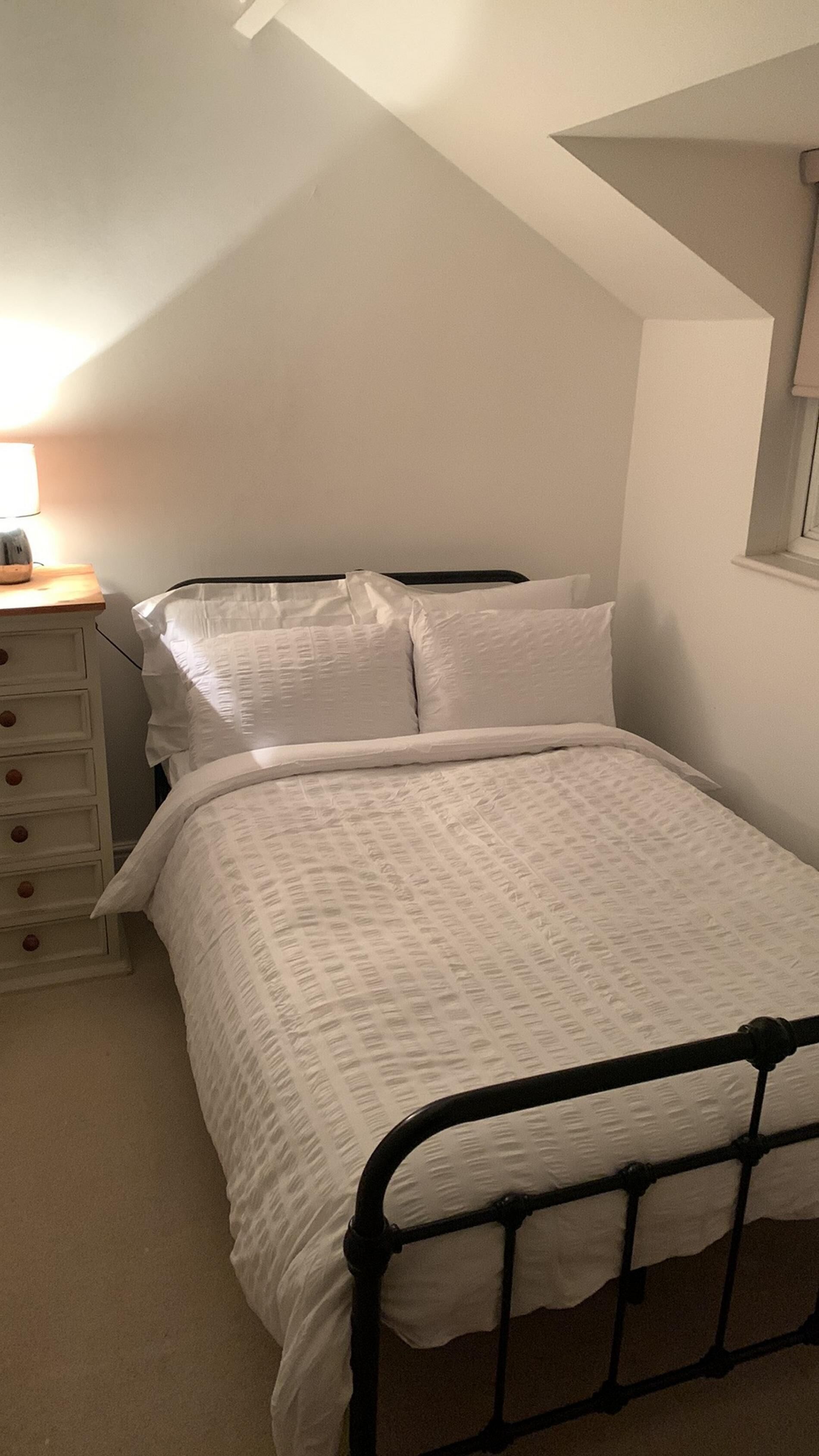 Un dormitorio con una cama individual, una mesita de noche y una lámpara.