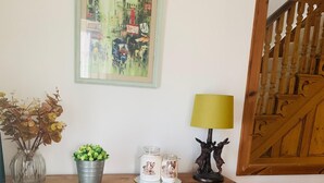 A wooden cabinet with a glass vase, a metal bucket with plants, and two glass jars with rabbit illustrations.