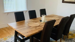 A dining area with a wooden table, black chairs, a woven placemat, and a decorative vase.
