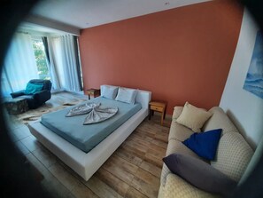 A bedroom with a large bed, a sofa, a small table, and a chair.