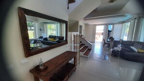 A spacious living area with a large mirror, a wooden console table, and a staircase leading to another room. - Beautiful house in Campeche for up to 16 people, heated pool and spa. (Florianópolis)