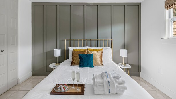 A neatly arranged hotel room with a large bed, bedside tables, and a window with a view. - Posh Old Village Townhome | Stylish Escape (Mount Pleasant)
