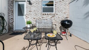 A patio with two tables, a grill, and a door. - Posh Old Village Townhome | Stylish Escape (Mount Pleasant)