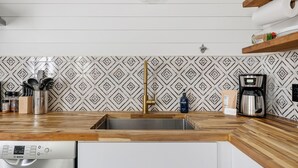 A kitchen with a stainless steel sink, wooden countertop, Bosch dishwasher, coffee maker, and patterned backsplash. - Posh Old Village Townhome | Stylish Escape (Mount Pleasant)