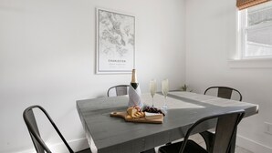 A dining table with a bottle of champagne, glasses, cheese, crackers, and grapes. - Posh Old Village Townhome | Stylish Escape (Mount Pleasant)