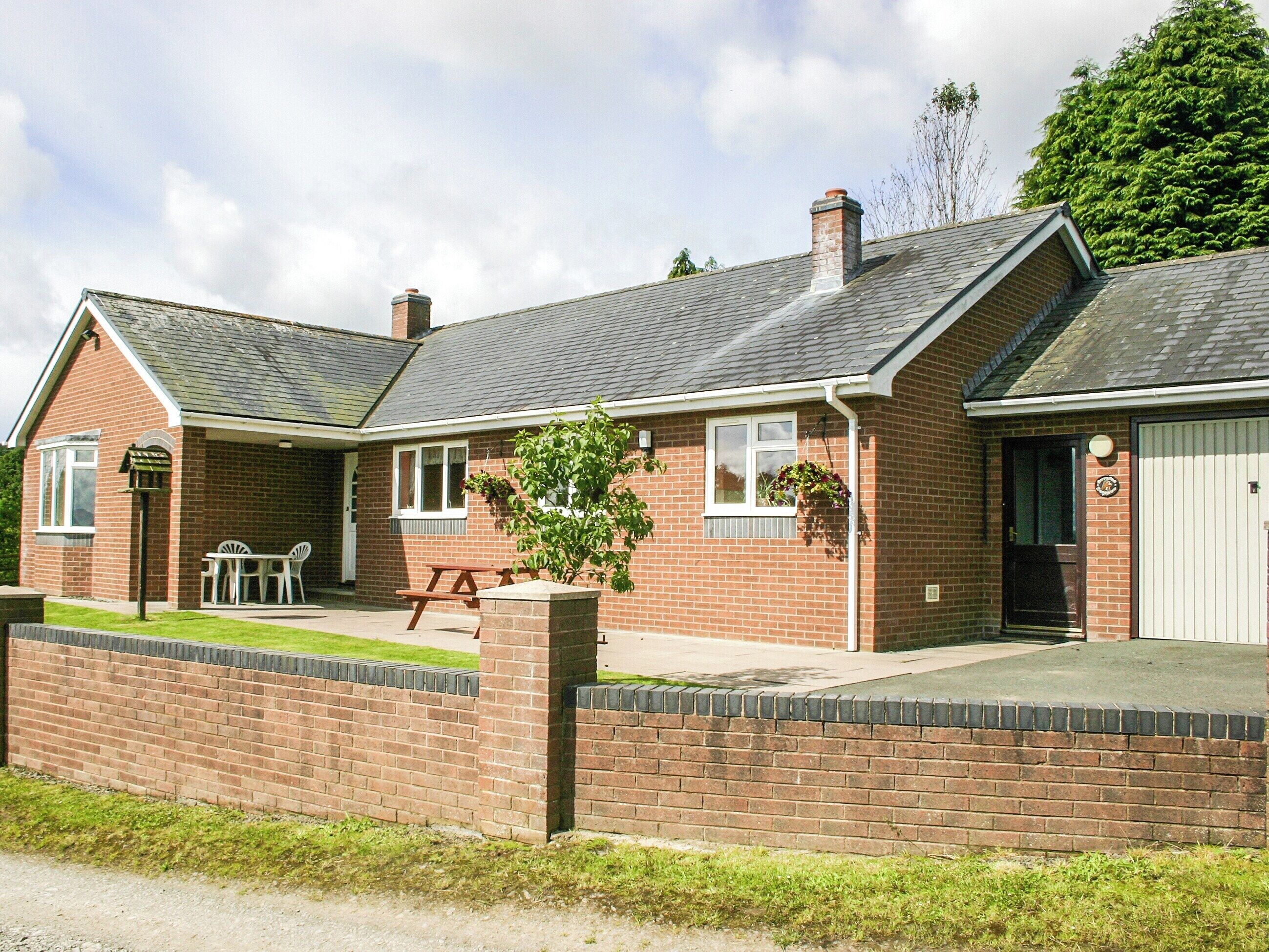A two-story brick house with a front porch, a garage, and a small garden area.