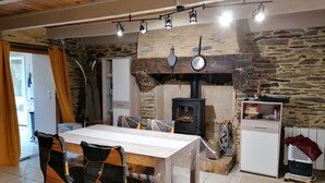 Uma sala de jantar acolhedora com parede de pedra, lareira a lenha e uma mesa branca.