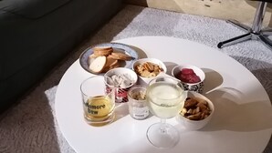 Uma mesa redonda branca com um fundo de parede de pedra, um sofá cinzento e uma almofada amarela.