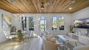 A spacious room with a wooden ceiling, large windows, a dining area, and a sofa. - ★Luxuriously Romantic One-Of-A-Kind Treehouse w/Canoe, Fire Pit and More★ (Santa Rosa Beach)